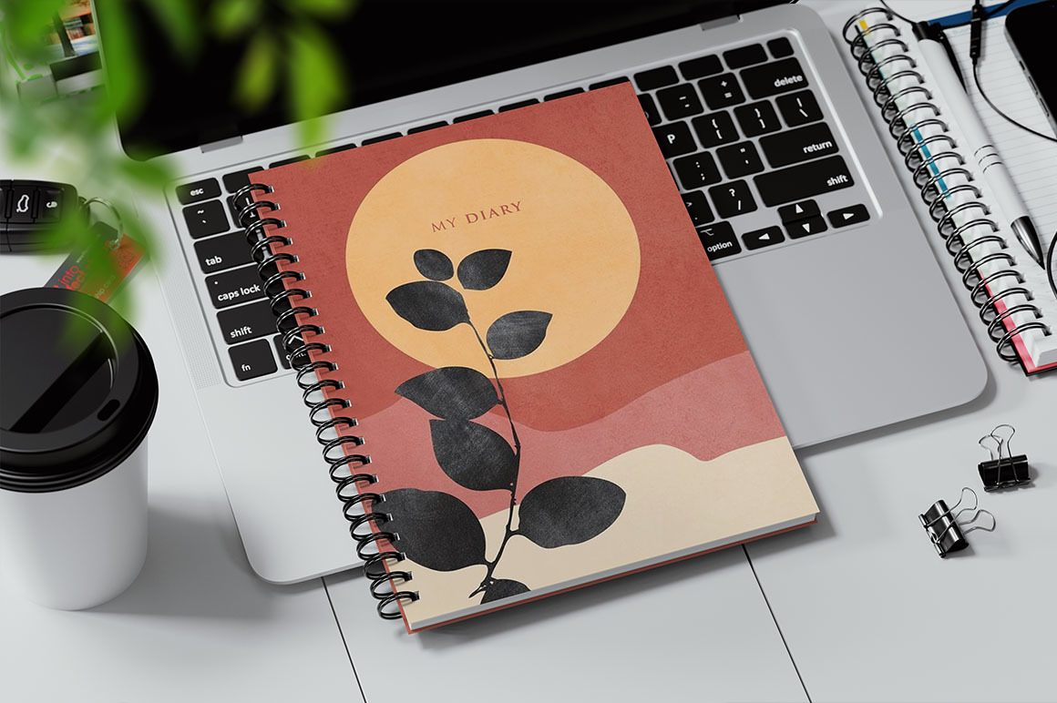 Spiral Bound Book on a Laptop Keyboard Mockup Spiral Bound Book on a Laptop Keyboard Mockup