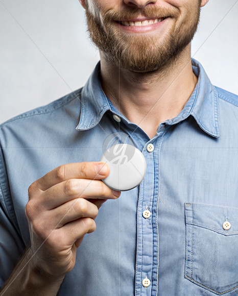 A Man Wearing a Denim Shirt Holds a Pin-Back Button Mockup