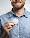 A Man Wearing a Denim Shirt Holds a Pin-Back Button Mockup