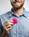 A Man Wearing a Denim Shirt Holds a Pin-Back Button Mockup