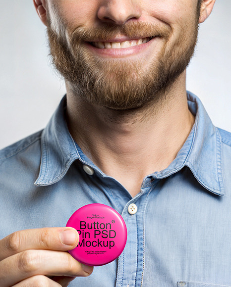 A Man Wearing a Denim Shirt Holds a Pin-Back Button Mockup