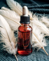 Ruby Oil Tincture Dropper Bottle with Feathers on Fabric Mockup
