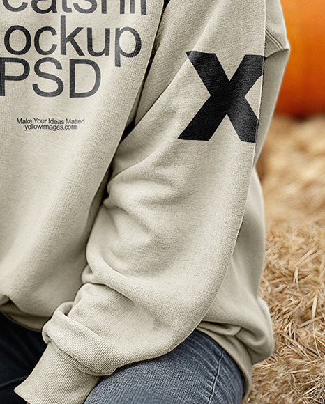 Young Woman in Sweatshirt Sitting on Hay Block with Pumpkins Around