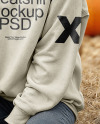 Young Woman in Sweatshirt Sitting on Hay Block with Pumpkins Around