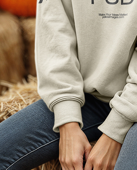 Young Woman in Sweatshirt Sitting on Hay Block with Pumpkins Around